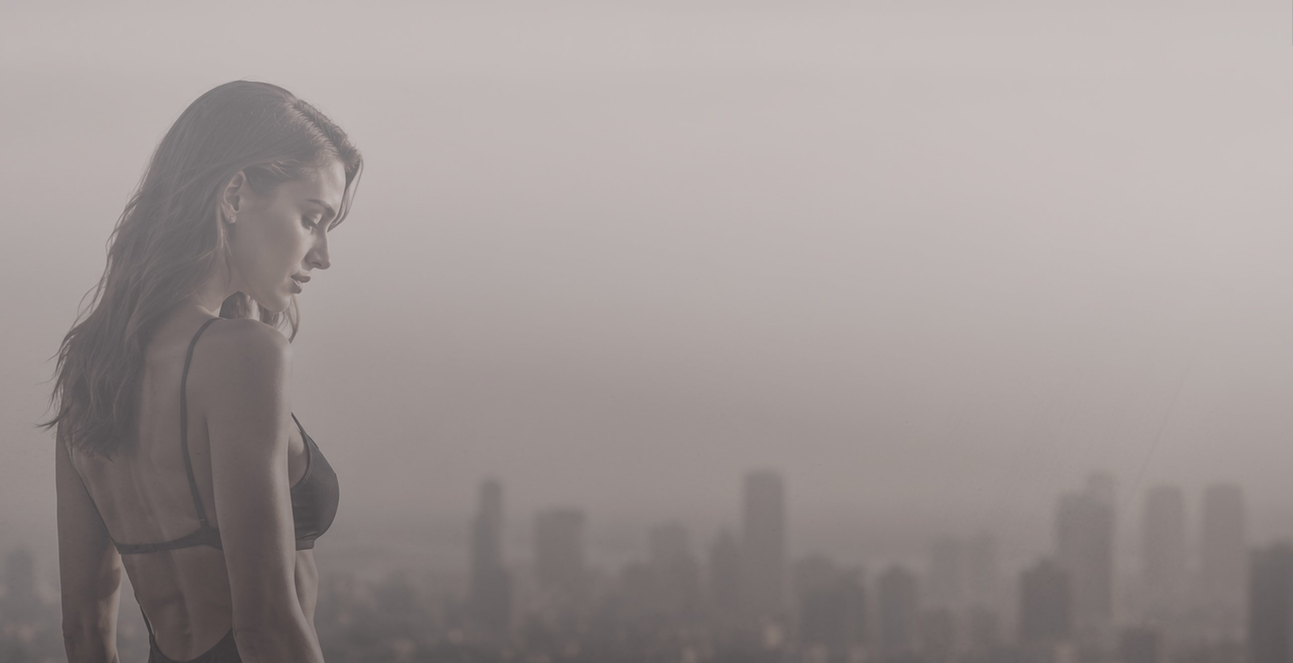 Woman gazing over a city skyline at dusk.