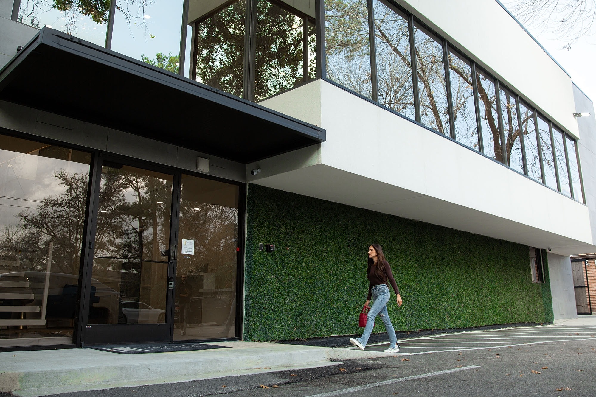 Woman walking by modern building entrance.