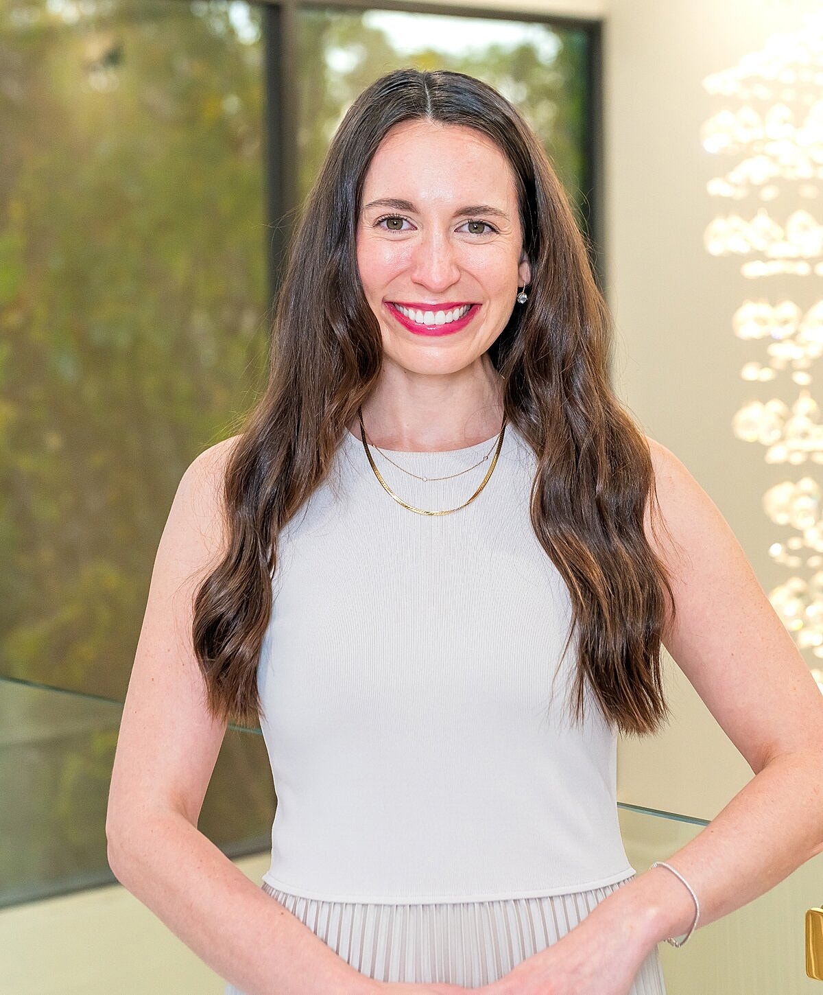 Smiling woman in a light dress, indoor setting.