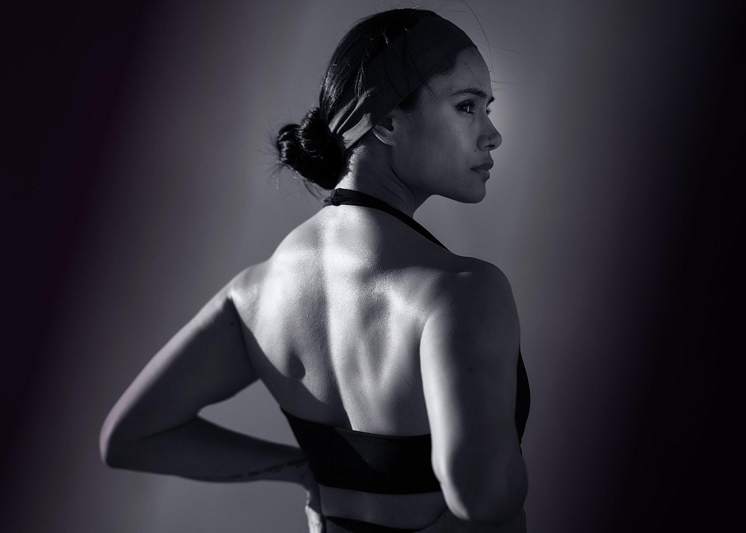 Woman in athletic wear, profile view, dramatic lighting.