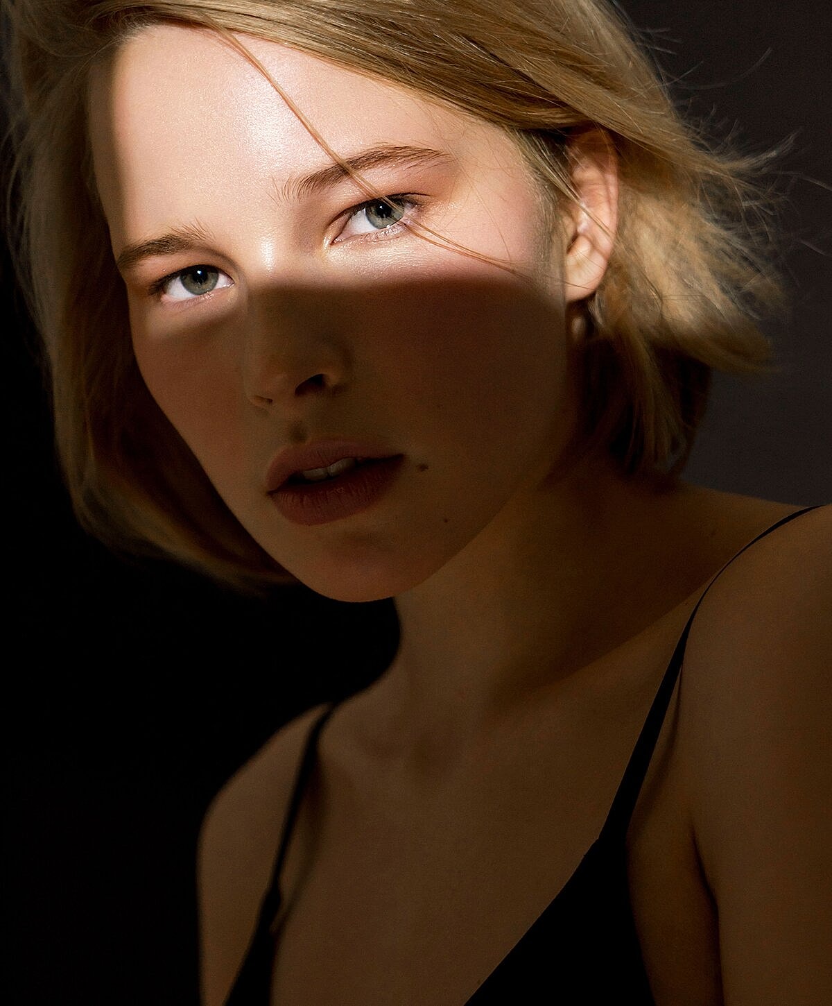 Close-up portrait with dramatic lighting and shadows.