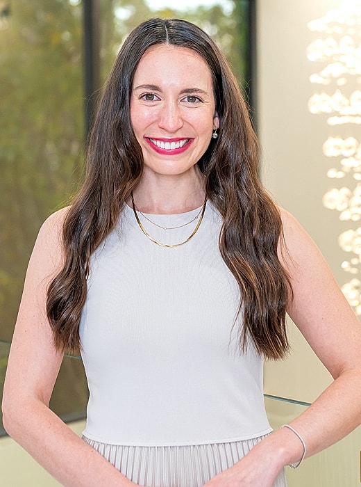 Smiling woman in elegant attire with long hair.