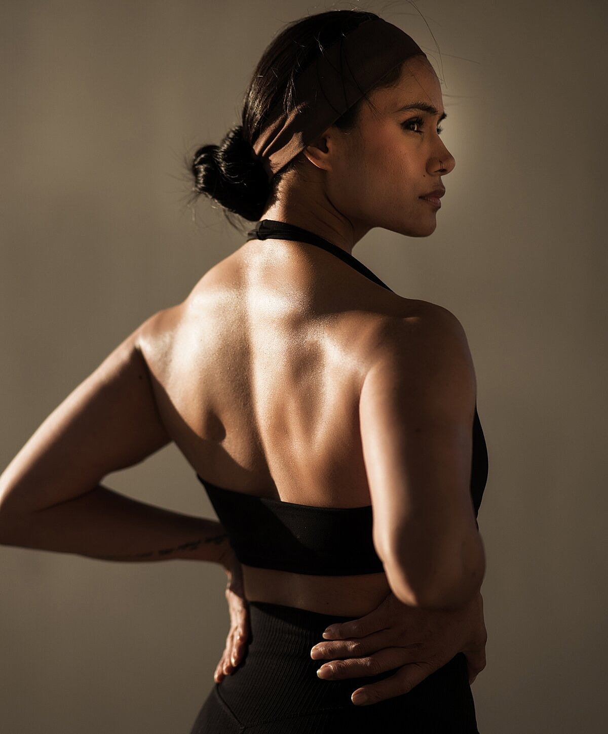 Fit woman in black athletic wear, back view.