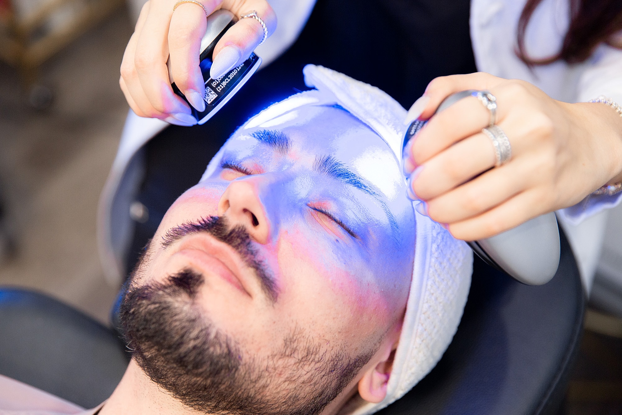 Man receiving facial treatment with blue light therapy.