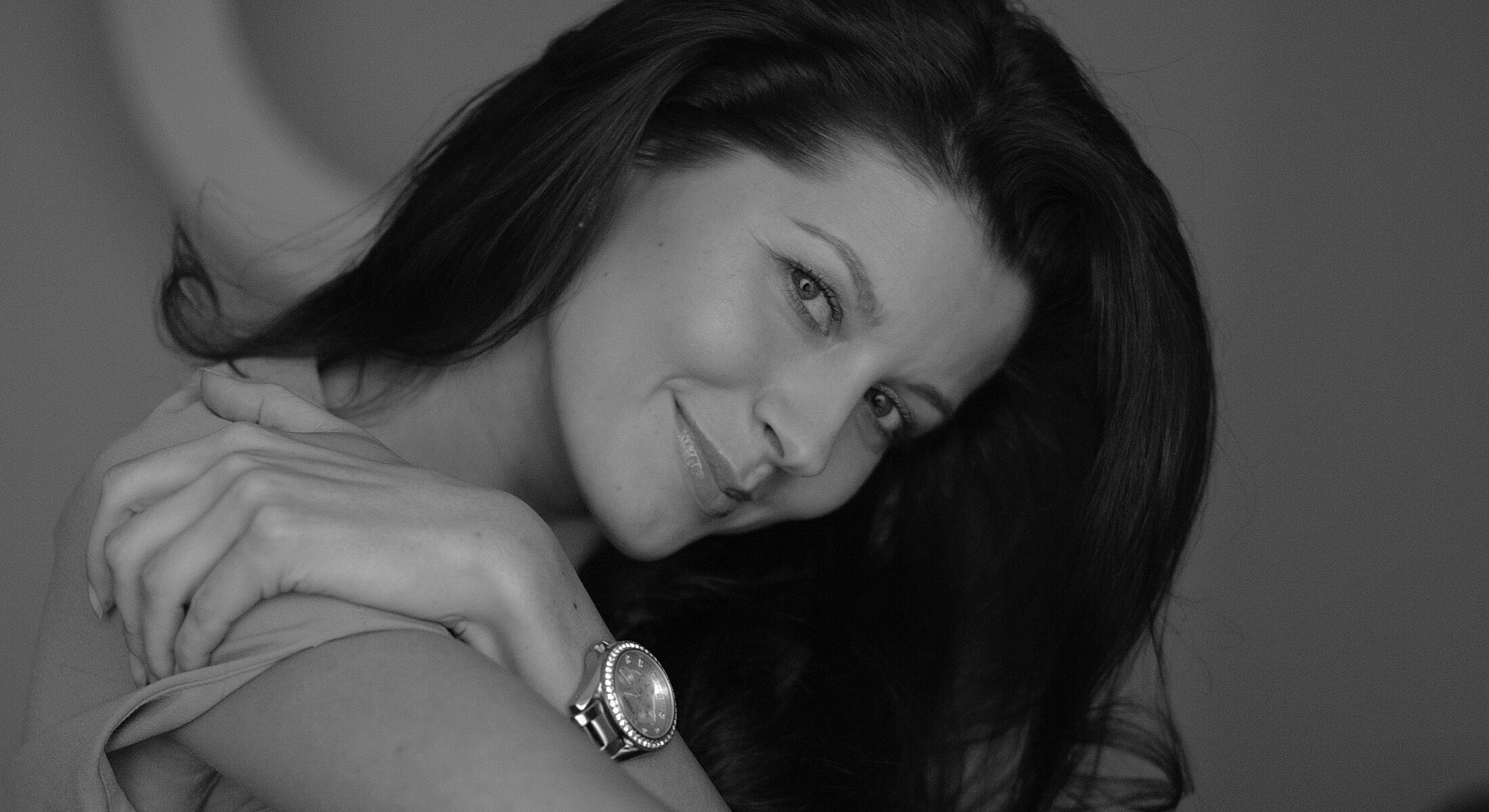 Woman smiling with long hair in black and white.