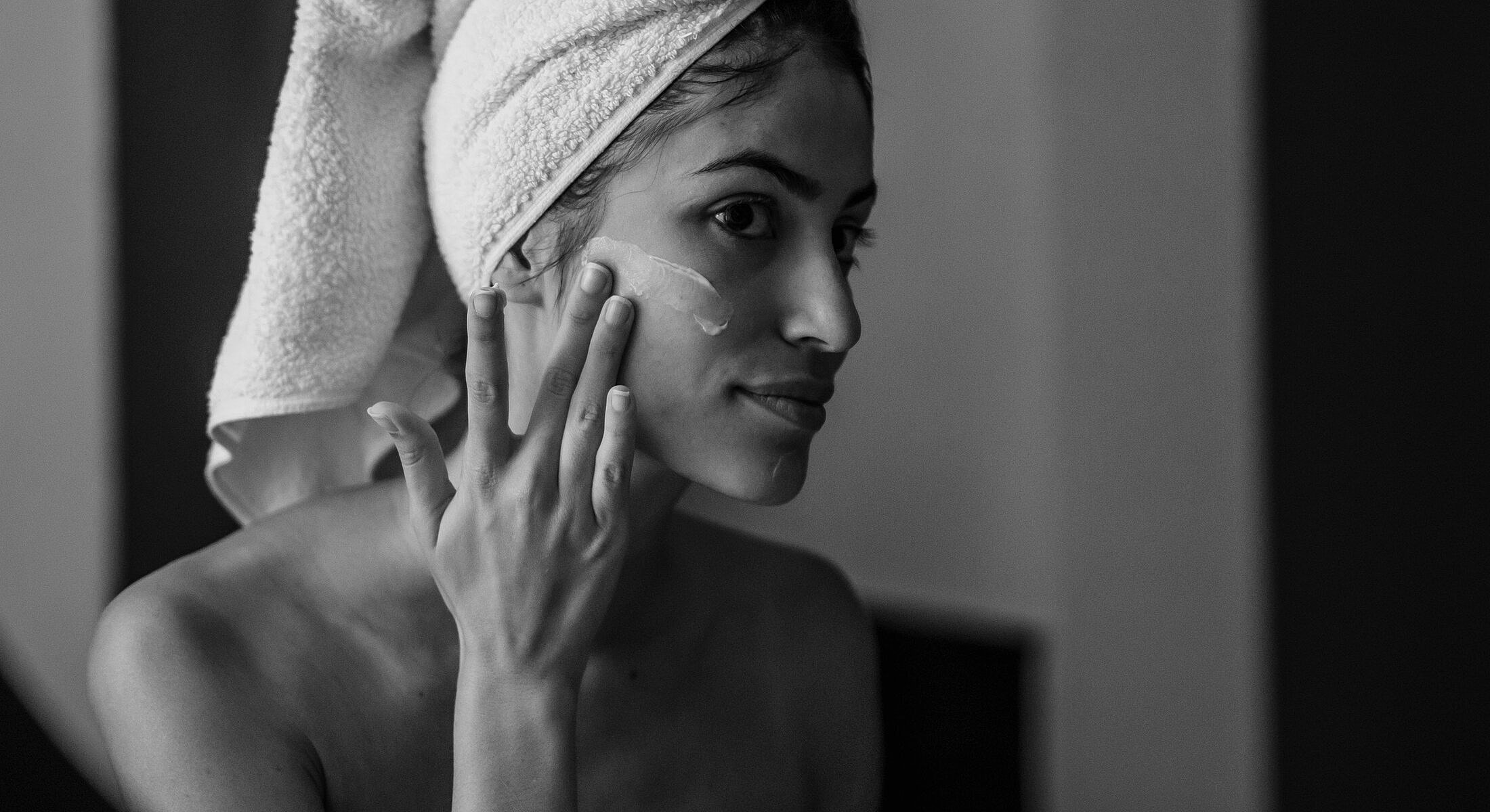Woman applying skincare in black and white.