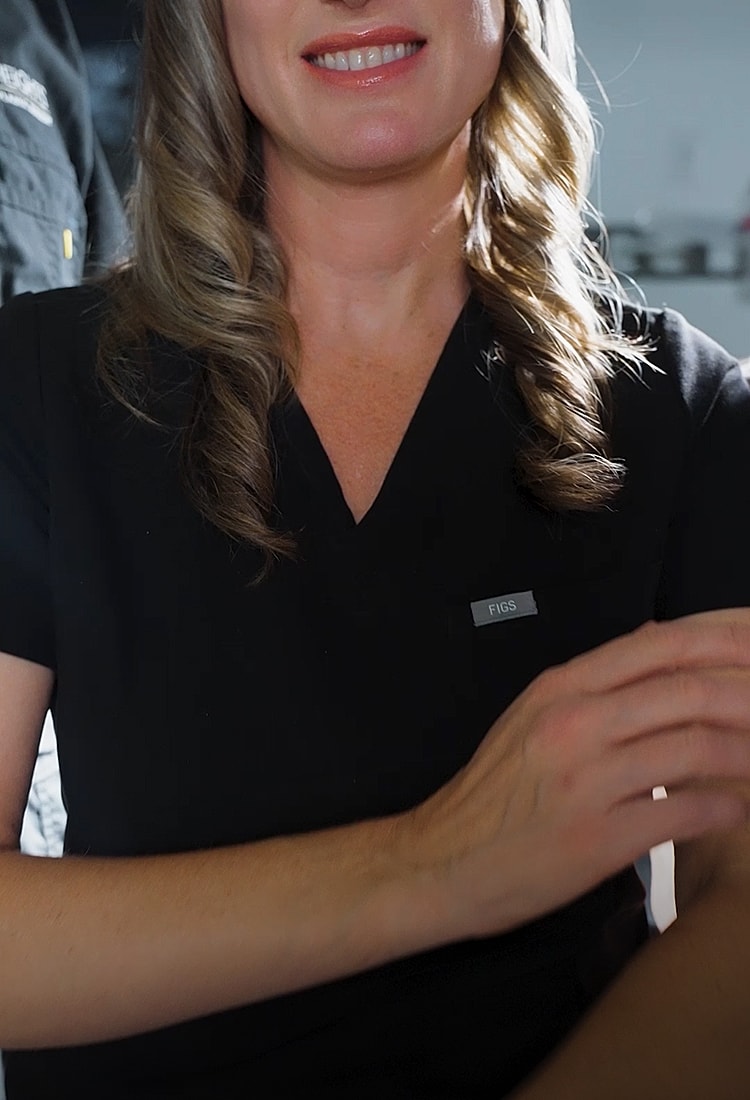 Healthcare professional in black scrubs smiling.